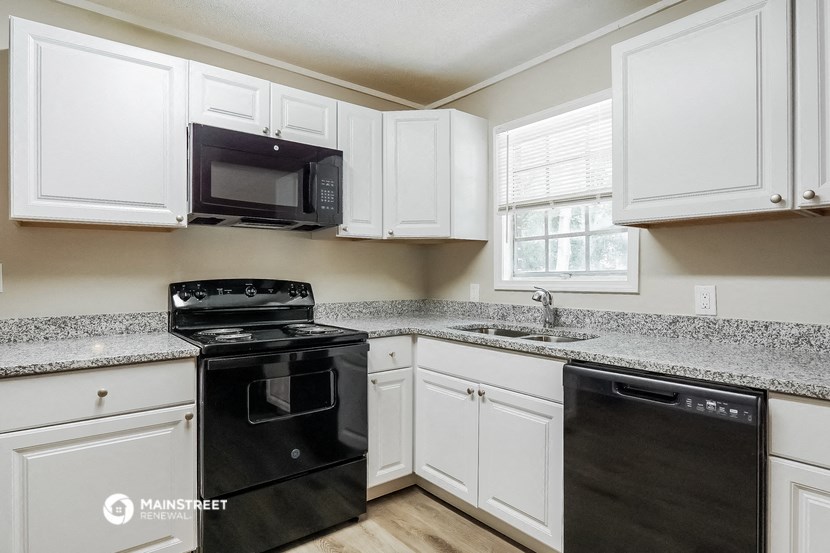 a kitchen with white cabinets and black appliances and granite counter tops