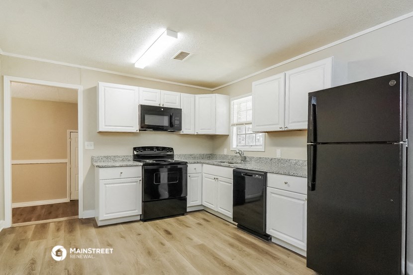 a kitchen with white cabinets and black appliances