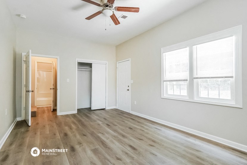 an empty living room with wood floors and a ceiling fan