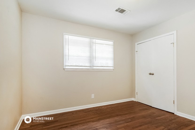 a bedroom with white walls and wood floors and a white door
