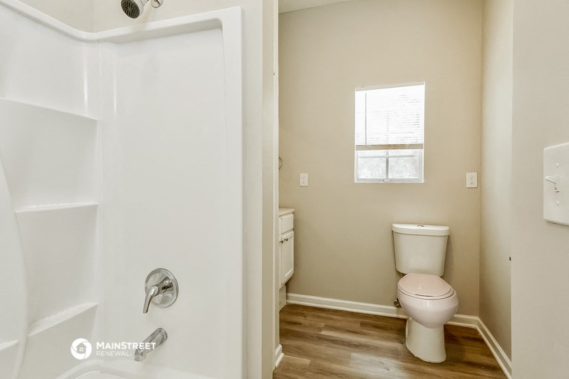 a bathroom with a toilet and a shower and a window