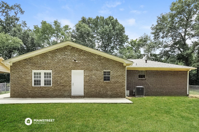 the front of a brick house with a white door    and a lawn
