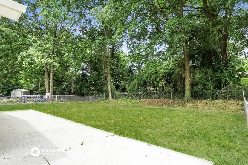 a yard with a chain link fence and grass and trees