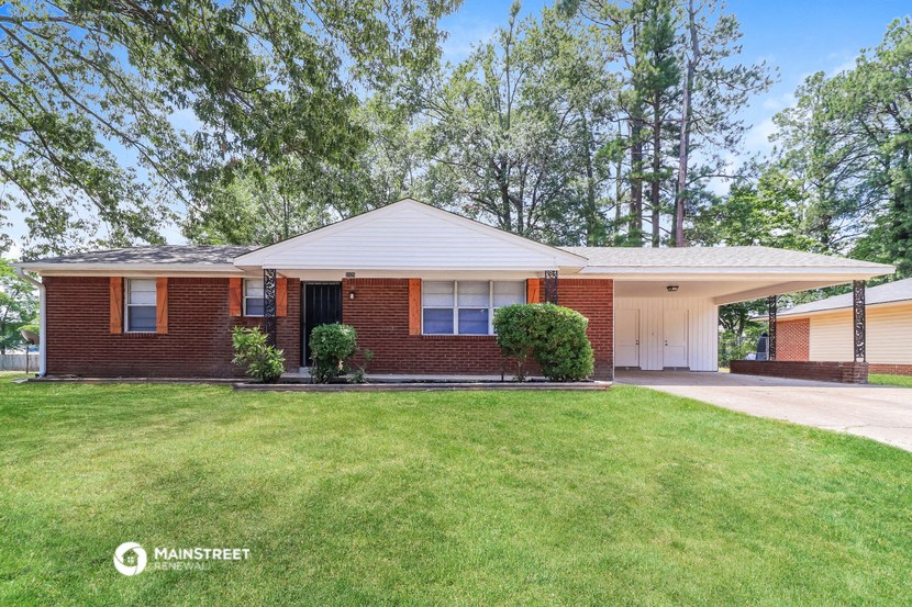 a red brick house with a lawn and trees