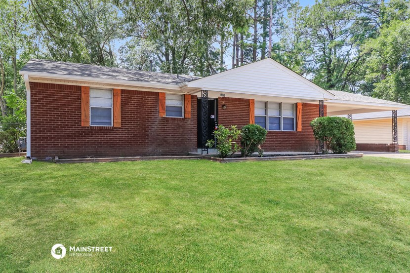 a small brick house with a lawn in front of it