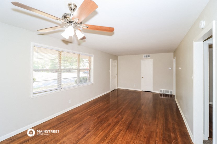 an empty living room with wood floors and a ceiling fan