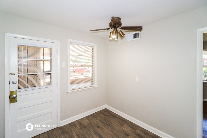 the living room of a home with a ceiling fan and a door