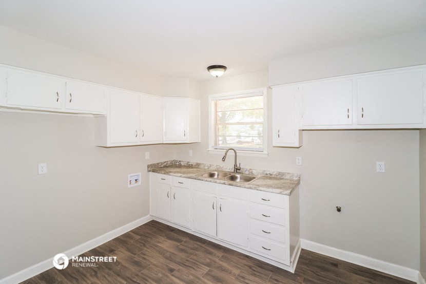a kitchen with white cabinets and a sink and a window