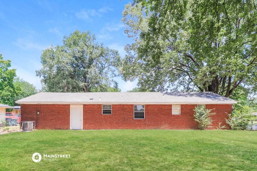 an old brick house with a grassy yard and trees