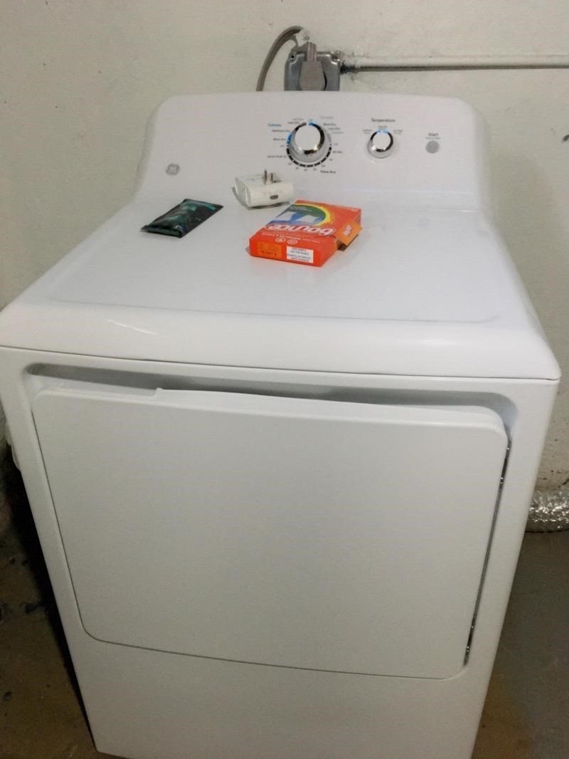 A white washing machine with a box of detergent on top.