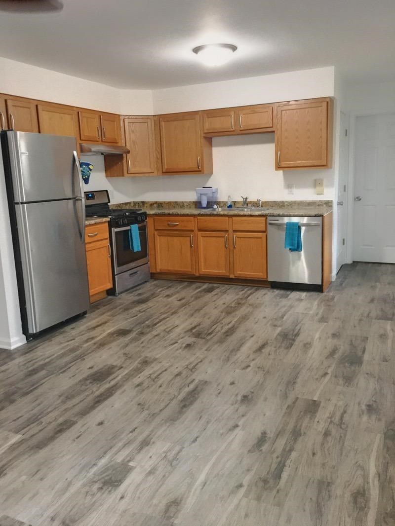 A kitchen with wooden cabinets and a grey floor.