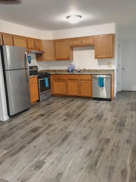 A kitchen with wooden cabinets and a grey floor.