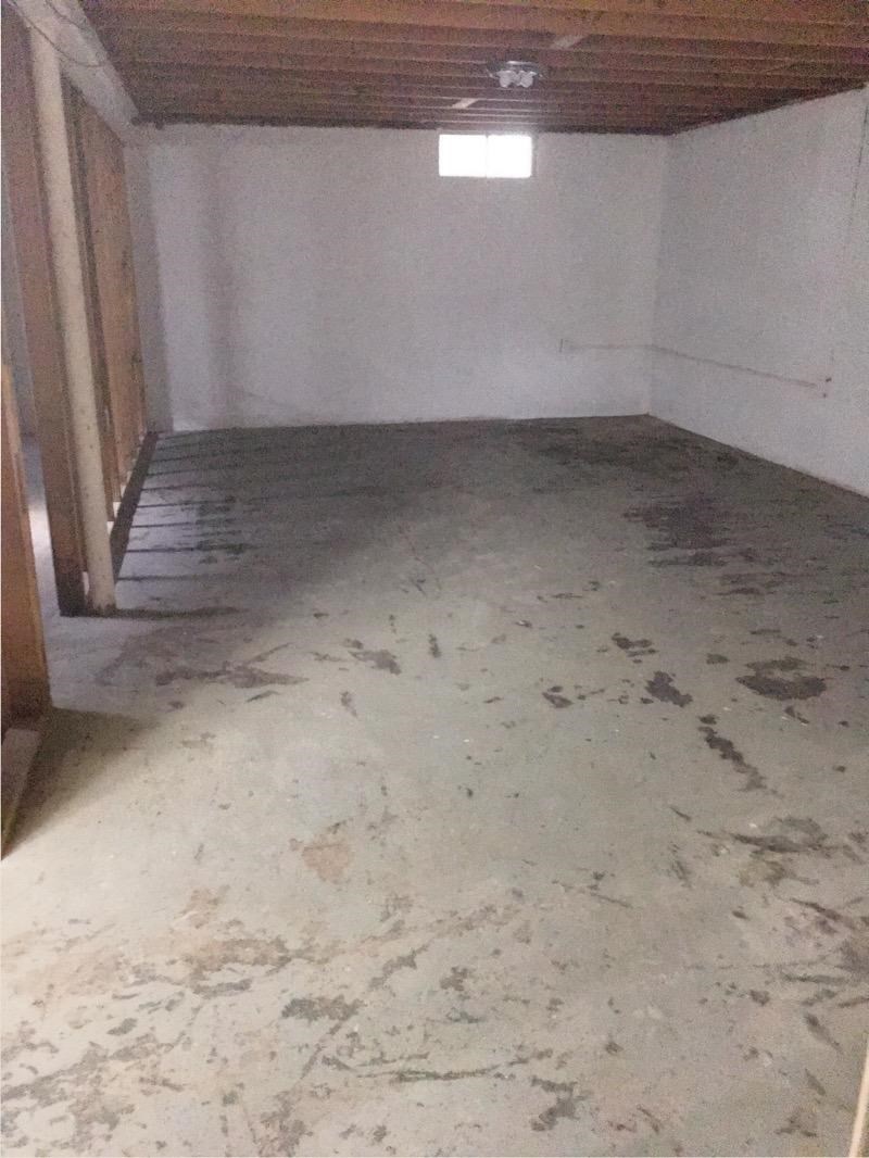 A room with a concrete floor and wooden beams on the ceiling.