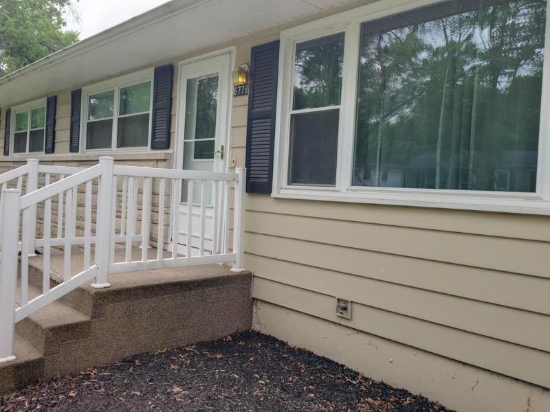 A house with a white railing and steps leading to a door.