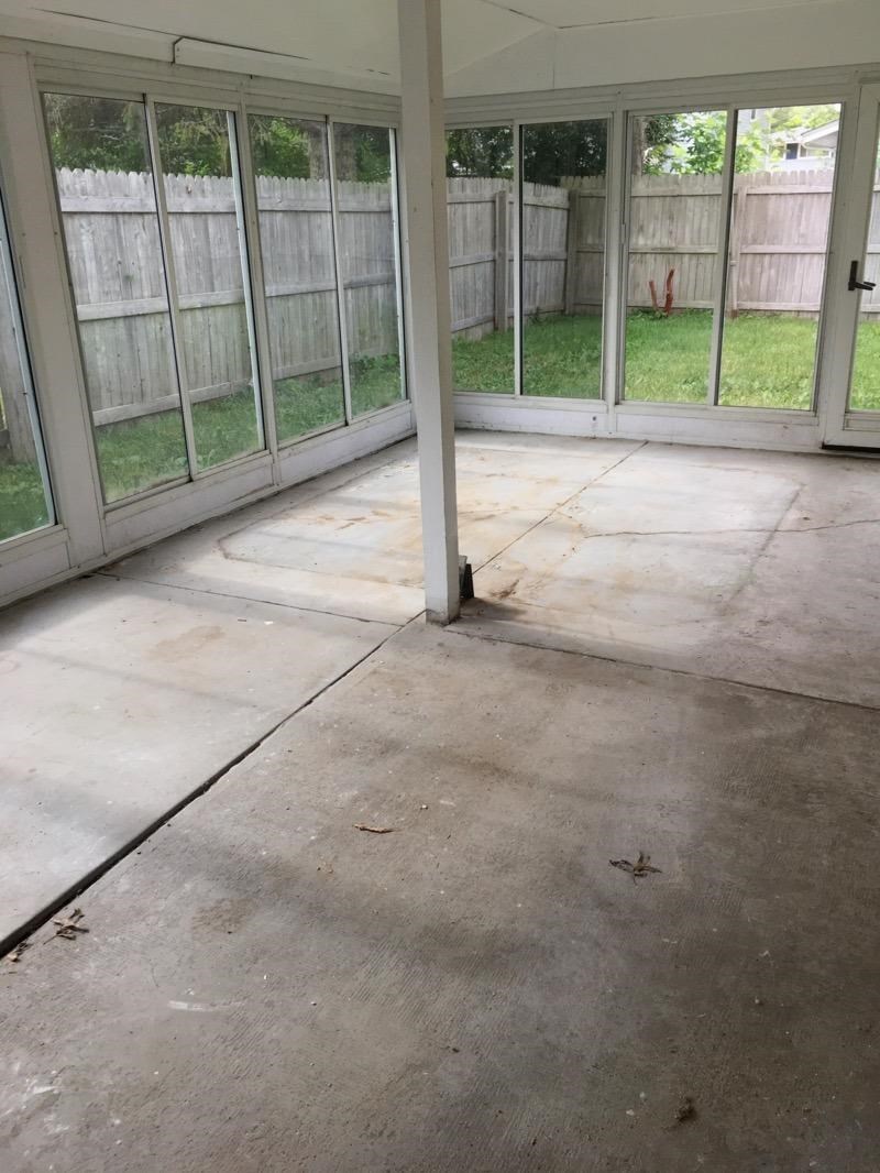 A sunny backyard with a white fence and a sliding glass door.
