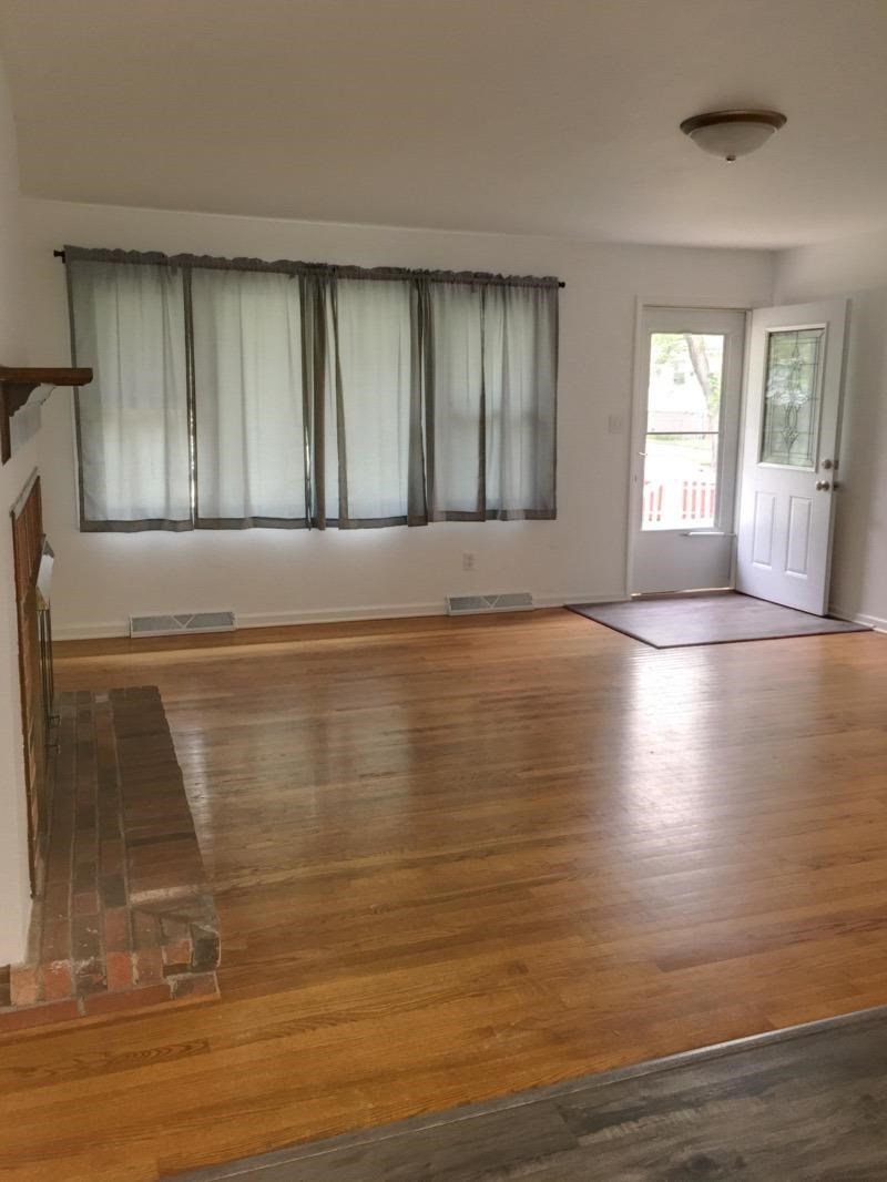 A room with a wooden floor and a window with curtains.