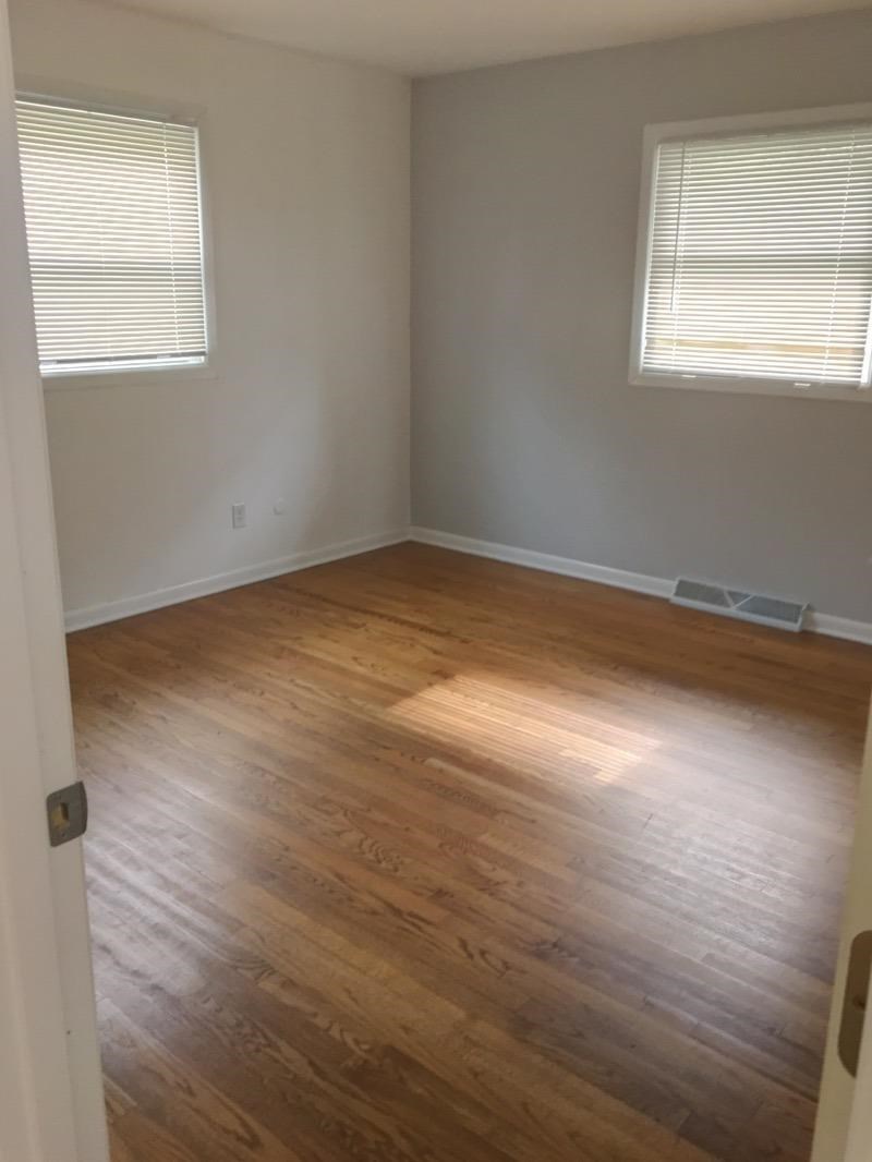 A room with wooden flooring and a window with blinds.