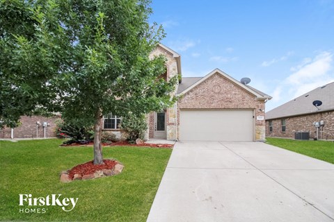 a home with a white garage door and a tree in the yard