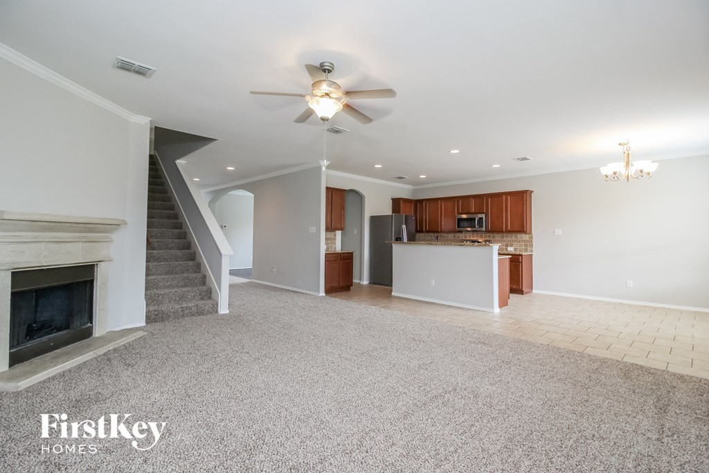 an empty living room with a fireplace and a kitchen