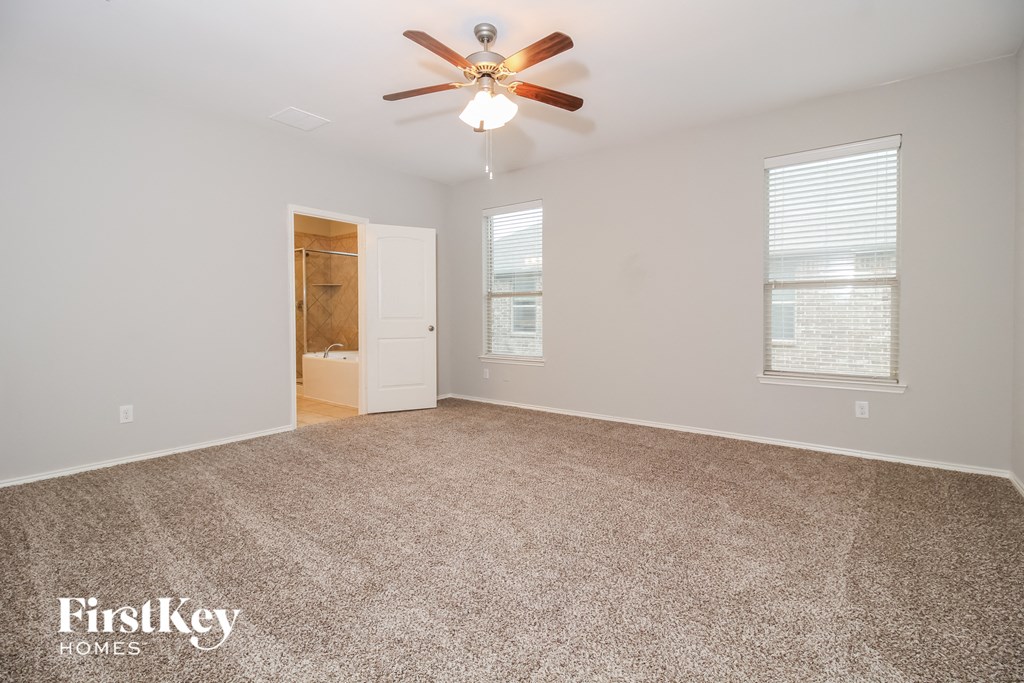 a spacious living room with carpet and a ceiling fan