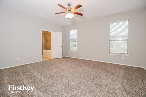 a spacious living room with carpet and a ceiling fan