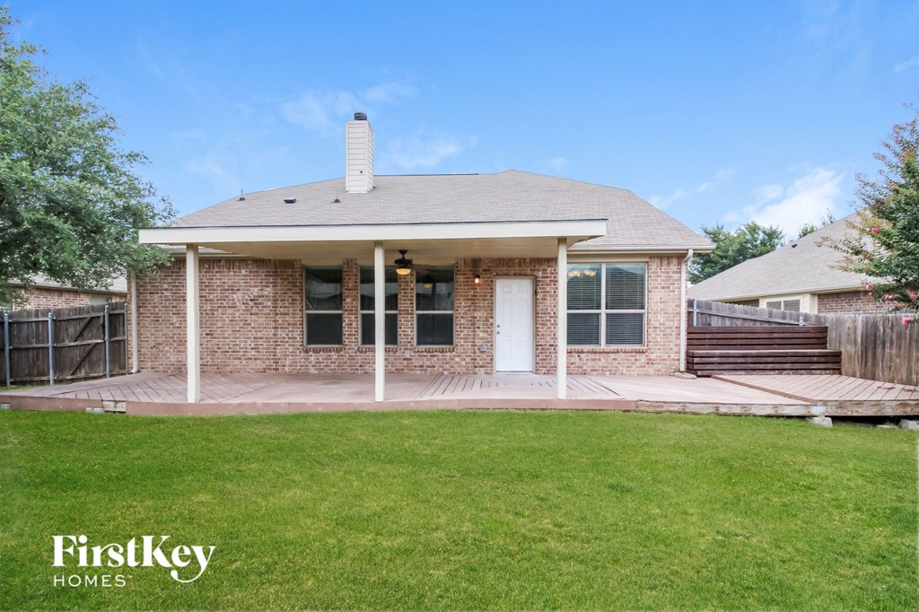 a small brick house with a porch and a lawn