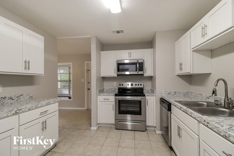 A kitchen with white cabinets and a marble countertop.