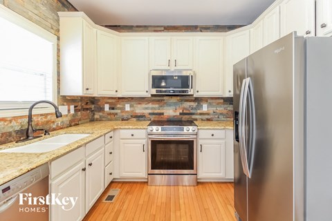a kitchen with white cabinets and stainless steel appliances and a wooden floor