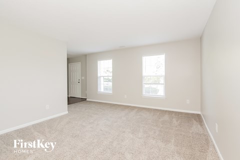 a spacious living room with white walls and carpet