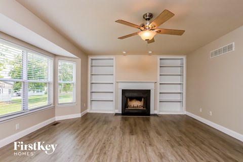 A spacious room with a fireplace and a ceiling fan.