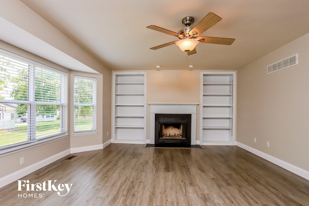 A spacious room with a fireplace and a ceiling fan.