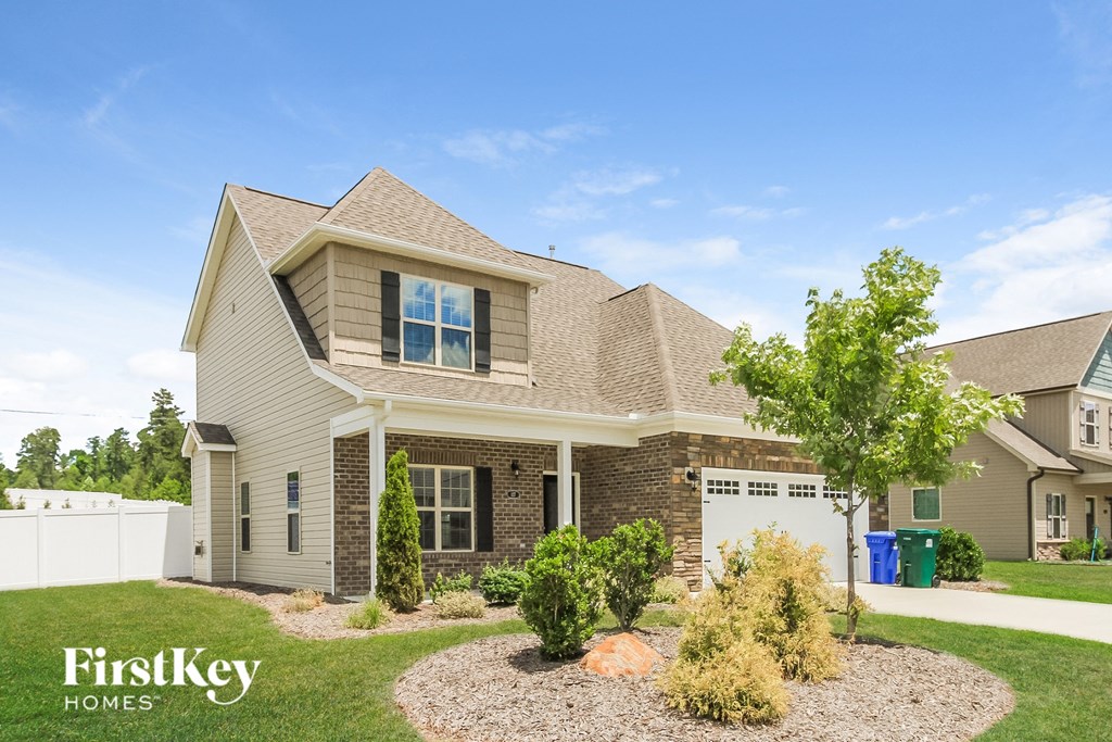 a beige and brown house with a yard and a white fence