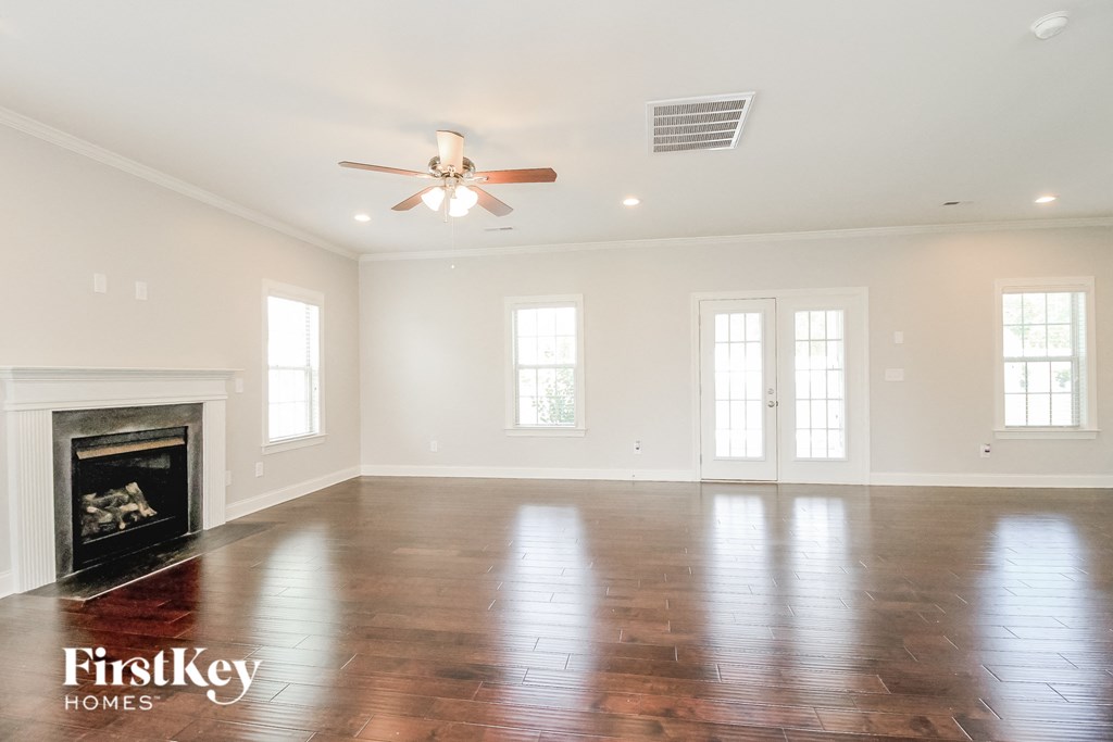 an empty living room with a fireplace and a ceiling fan