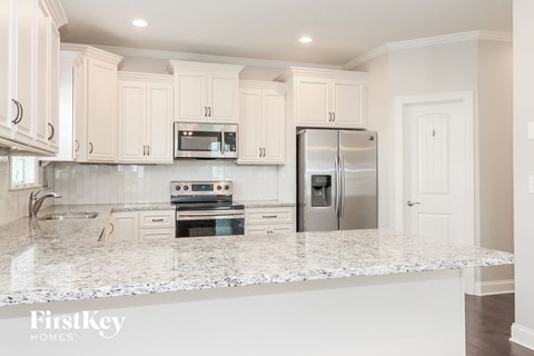 a kitchen with white cabinets and a marble counter top