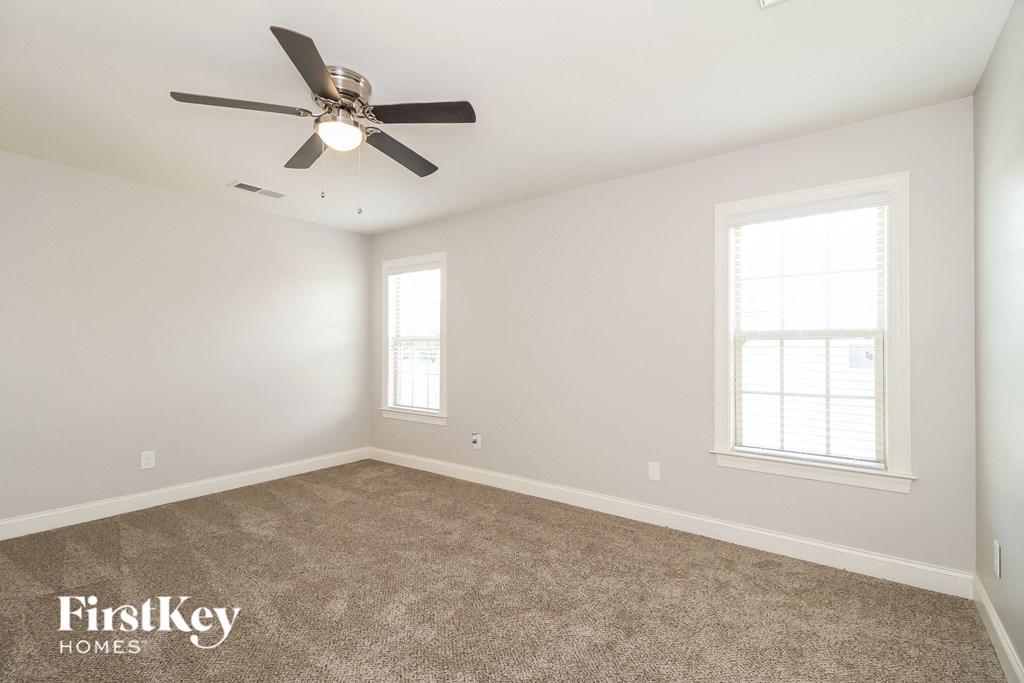 an empty room with a ceiling fan and two windows