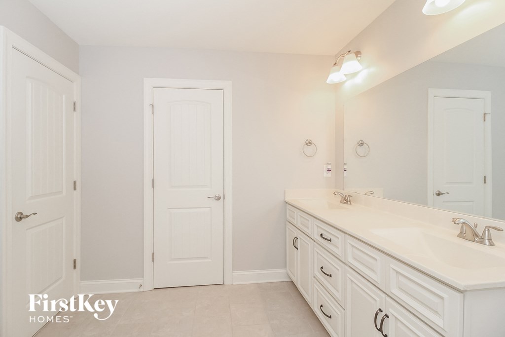 a white bathroom with two sinks and two doors