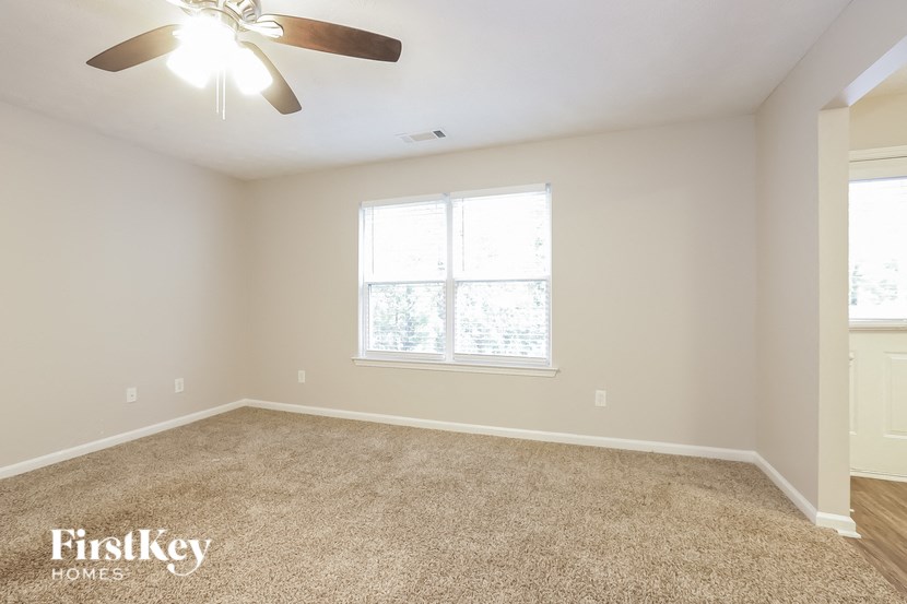 A room with a carpeted floor and a ceiling fan.