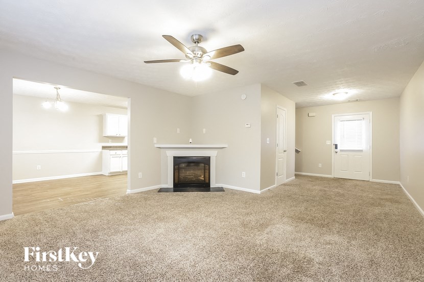 A spacious living room with a fireplace and a ceiling fan.