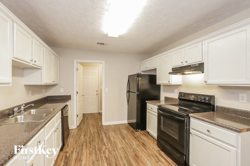 A kitchen with white cabinets and a black fridge.