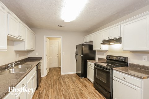 A kitchen with white cabinets and a black fridge.