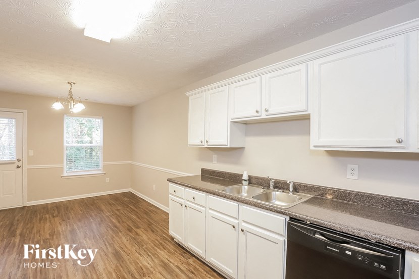 A kitchen with white cabinets and a black dishwasher.
