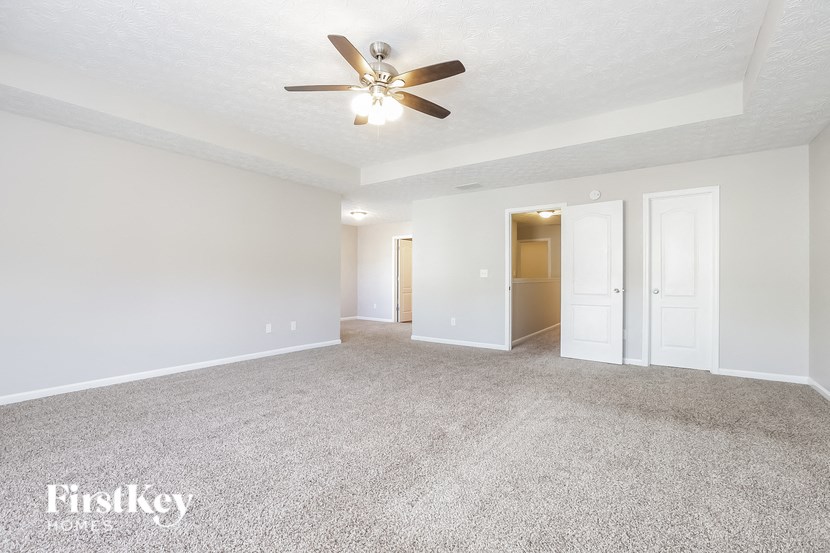 A spacious room with a ceiling fan and carpeted floor.