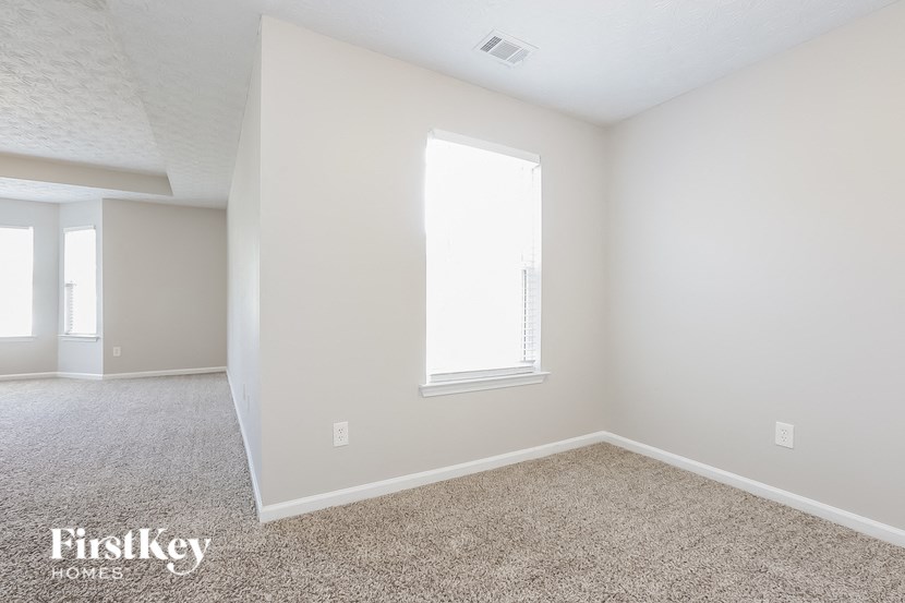 A room with a window and a carpeted floor.