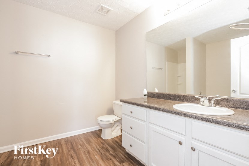 A bathroom with a toilet, sink, and mirror.