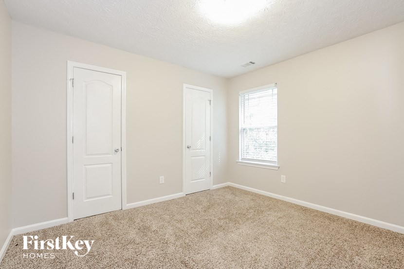 A room with two doors and a window, with a carpet on the floor.