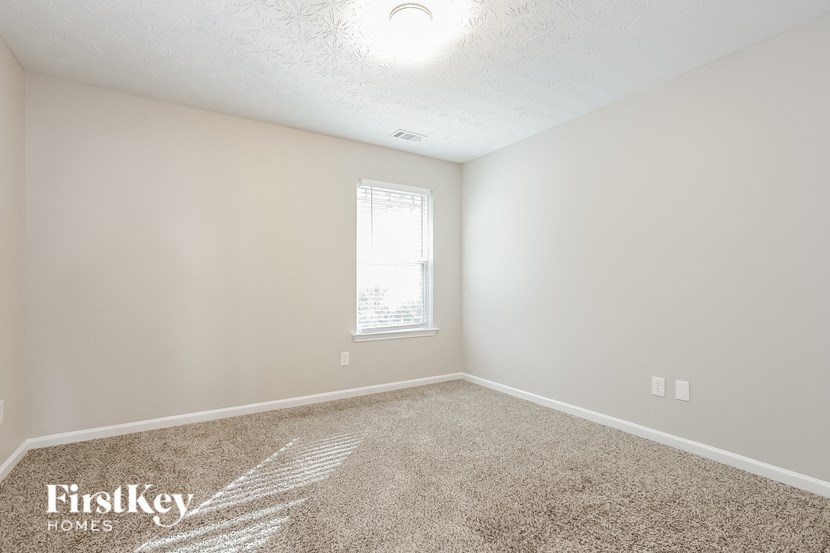 A room with a carpet floor and a window letting in light.