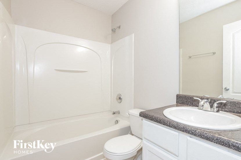 A white bathroom with a tub, toilet and sink.