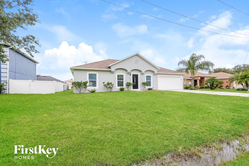 a home with a large lawn and a white house