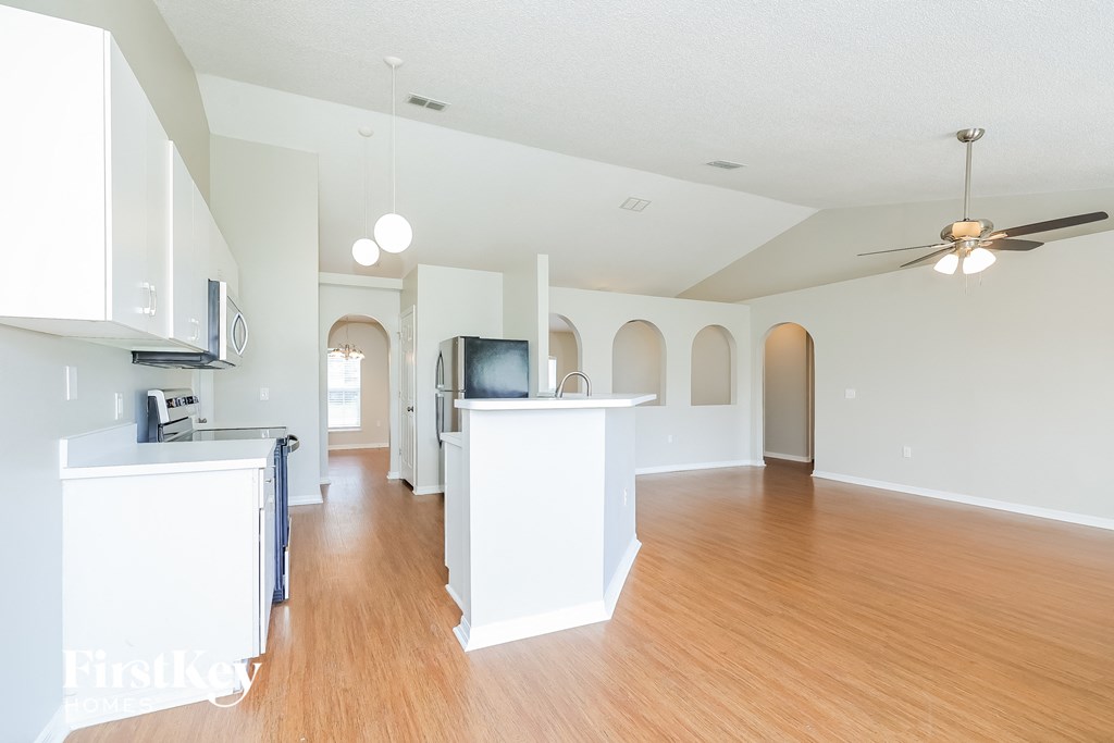 an open kitchen and living room with wood flooring and a ceiling fan
