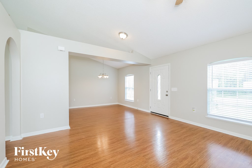 an empty living room with wood floors and white walls